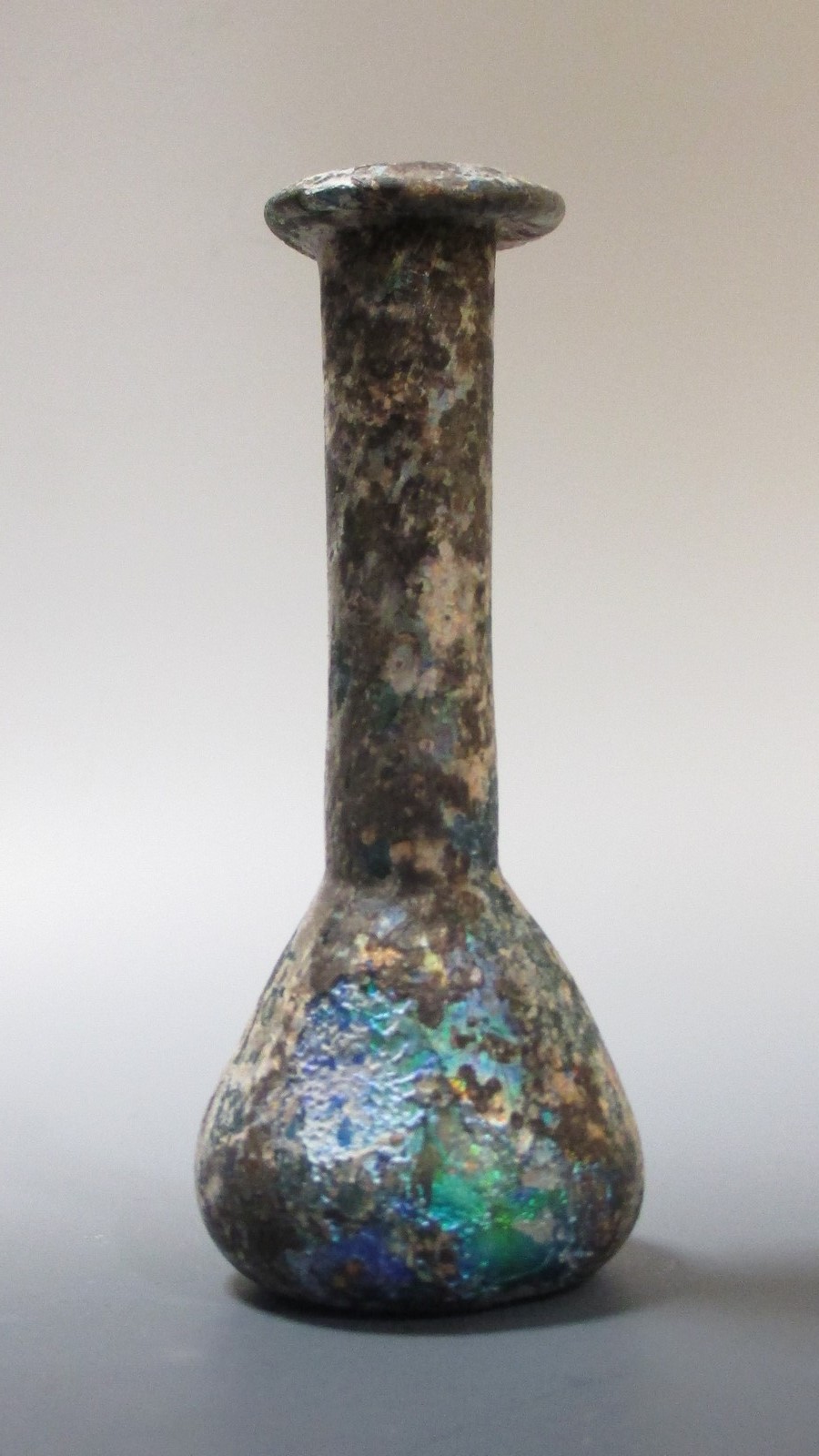 A small Roman glass bottle in excavated condition, with certificate