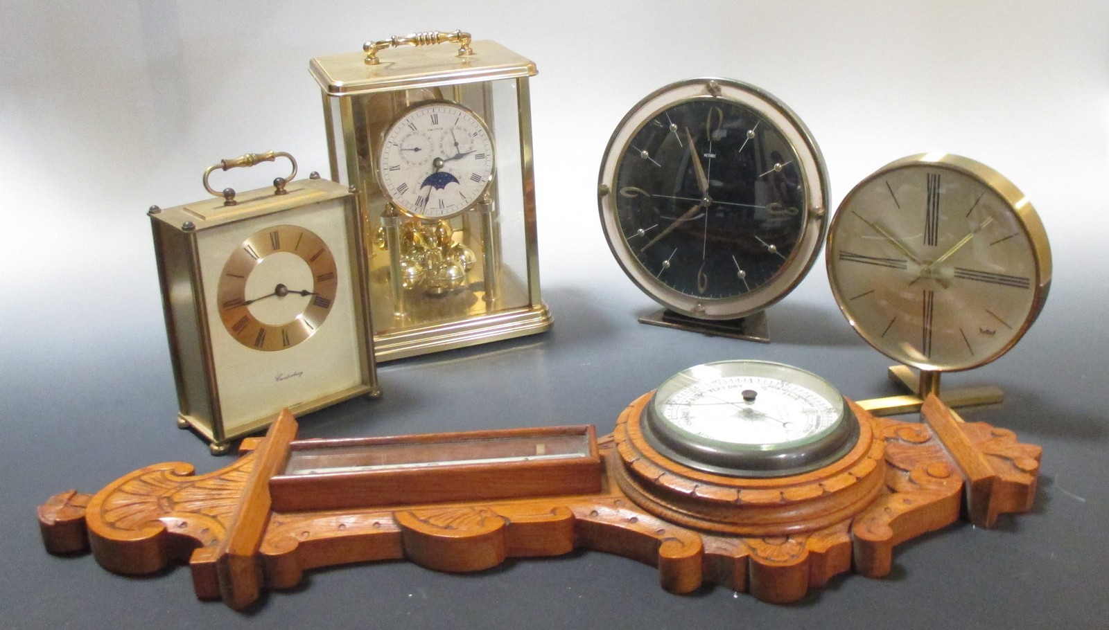 A small oak barometer by W E Pain, Cambridge together with four 20th century mantle and carriage