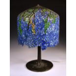 A Tiffany style 'Wisteria' table lamp, the shade of draping wisteria, in vivid blue leaded glass