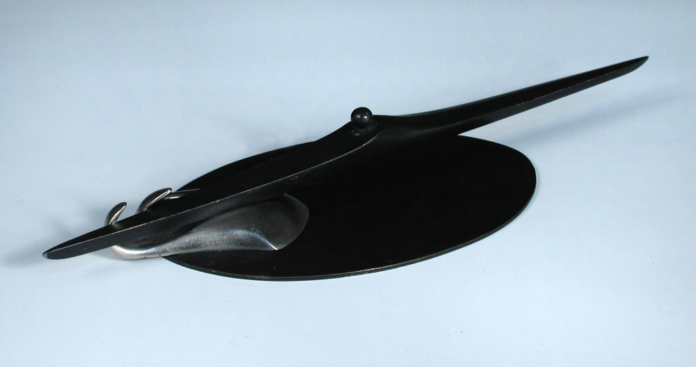 A Hagenauer patinated bronze model of a stylised boat, modelled riding a silvered wave on an oval