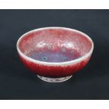 A miniature Ruskin high fired bowl, the circular footed form glazed in reds and purples, dated 1933,