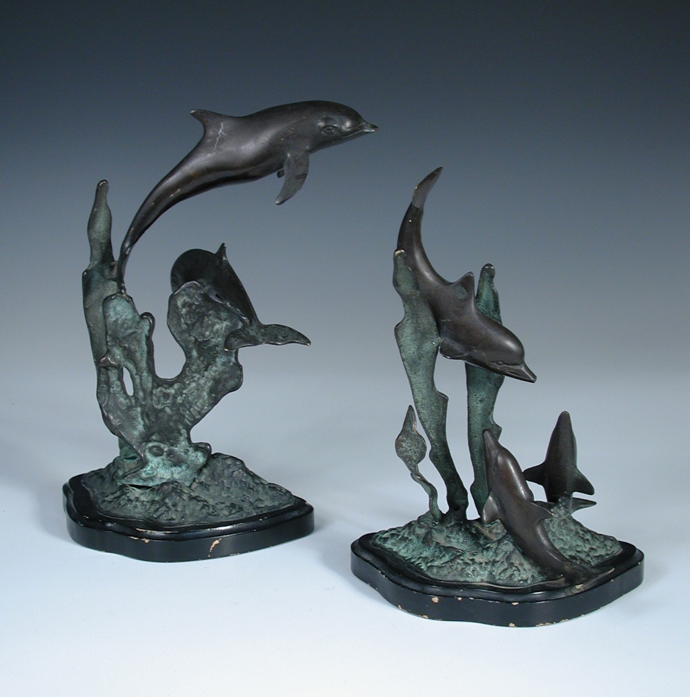 A 20th century bronze group of dolphins, modelled as a mother and two juveniles amidst weeds,