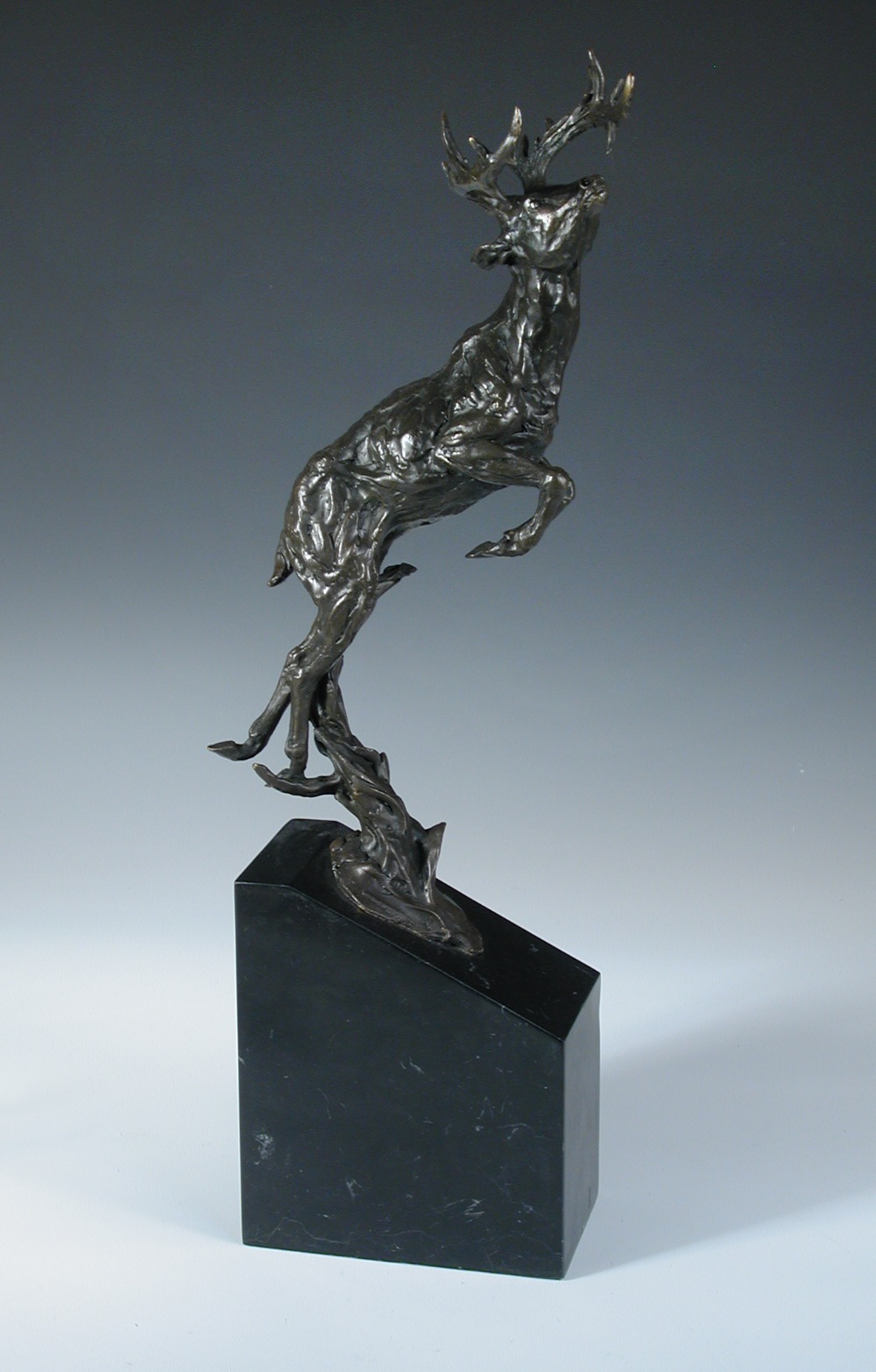 A contemporary bronze model of a leaping stag, mounted on a black marble plinth base, signed '