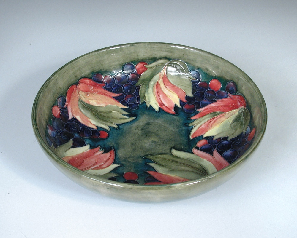 A Moorcroft leaves and berries pattern bowl, of circular form decorated to a green ground, painted