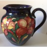 A Moorcroft African lily pattern jug, decorated to a blue ground, together with a Moorcroft Orchid