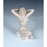 A Wallendorf porcelain model of a female nude, modelled kneeling, her hands behind her head, printed