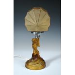 An Art Deco amber glass figural table lamp, modelled as a female nude kneeling on a rocky base,