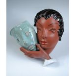 A Goldscheider Art Deco wall mask, the terracotta head of a young woman holds a theatrical mask to