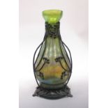 An Art Nouveau iridescent glass vase, the bottle form within a patinated copper frame of stylised