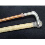 Two corded riding crops with white metal handles, one in the form of a golf ball, bearing European