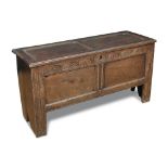 A small 17th century oak chest, with panelled top, carved frieze rail, on bench end supports 66cm