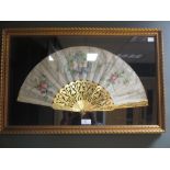 A framed fan with painted leaf