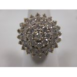 A diamond cluster ring, a small central round brilliant cut diamond surrounded by three rings of