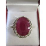 A ruby ring with diamond surround, the oval ruby mixed cut ruby, 15.8 x 11.8mm, set in four claws to