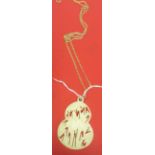 A Japanese ivory gourd shaped pendant carved with irises