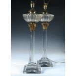 A pair of late 19th century glass column oil lamps with shades, the ribbed cup shaped receivers