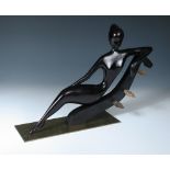 A Hagenauer ebonised wood and brass model of a stylised female nude, modelled reclining on a gondola