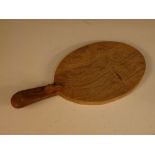 A Robert 'Mouseman' Thompson oak cheese board, the oval paddle with handle and carved mouse