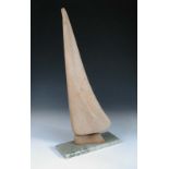 A 20th century carved wood sculpture of a stylised sailing yacht, with pivoting sail, mounted on a