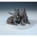 A Goldscheider model of two Scotties, the seated dog holds a bone whilst the other stands behind,