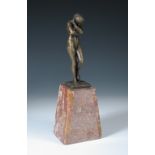 A bronze model of Eve after Auguste Rodin, modelled standing atop a red marble tapered base 30cm (