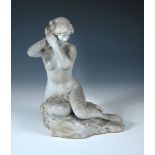 An early 20th century glazed stoneware model of a female nude, modelled styling her hair whilst
