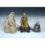 A soapstone luohan with wood stand, he sits in meditation with his right hand held under his chin,