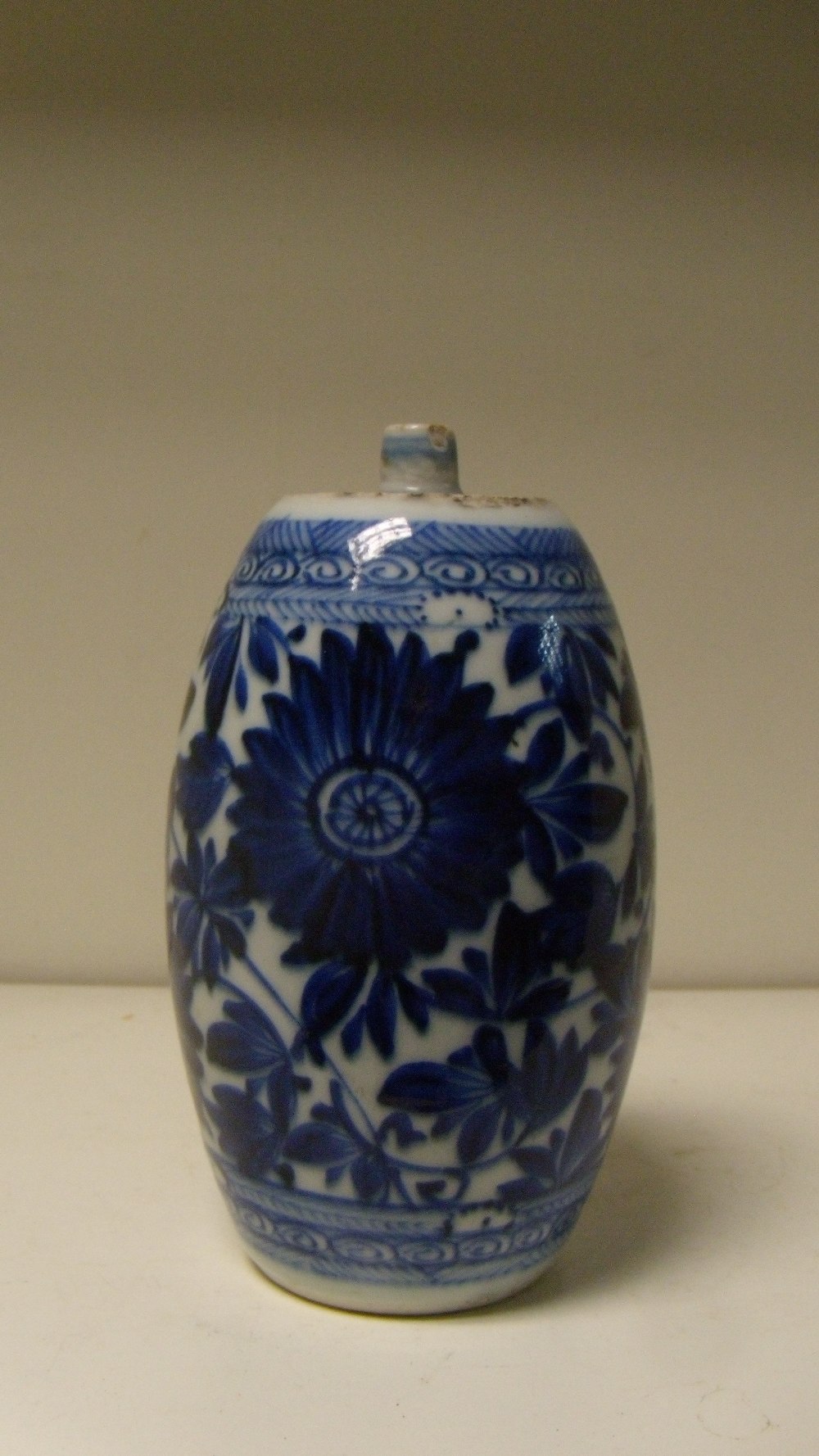 An 18th century blue and white barrel shaped vase, the flat top painted with scrolls enclosing a