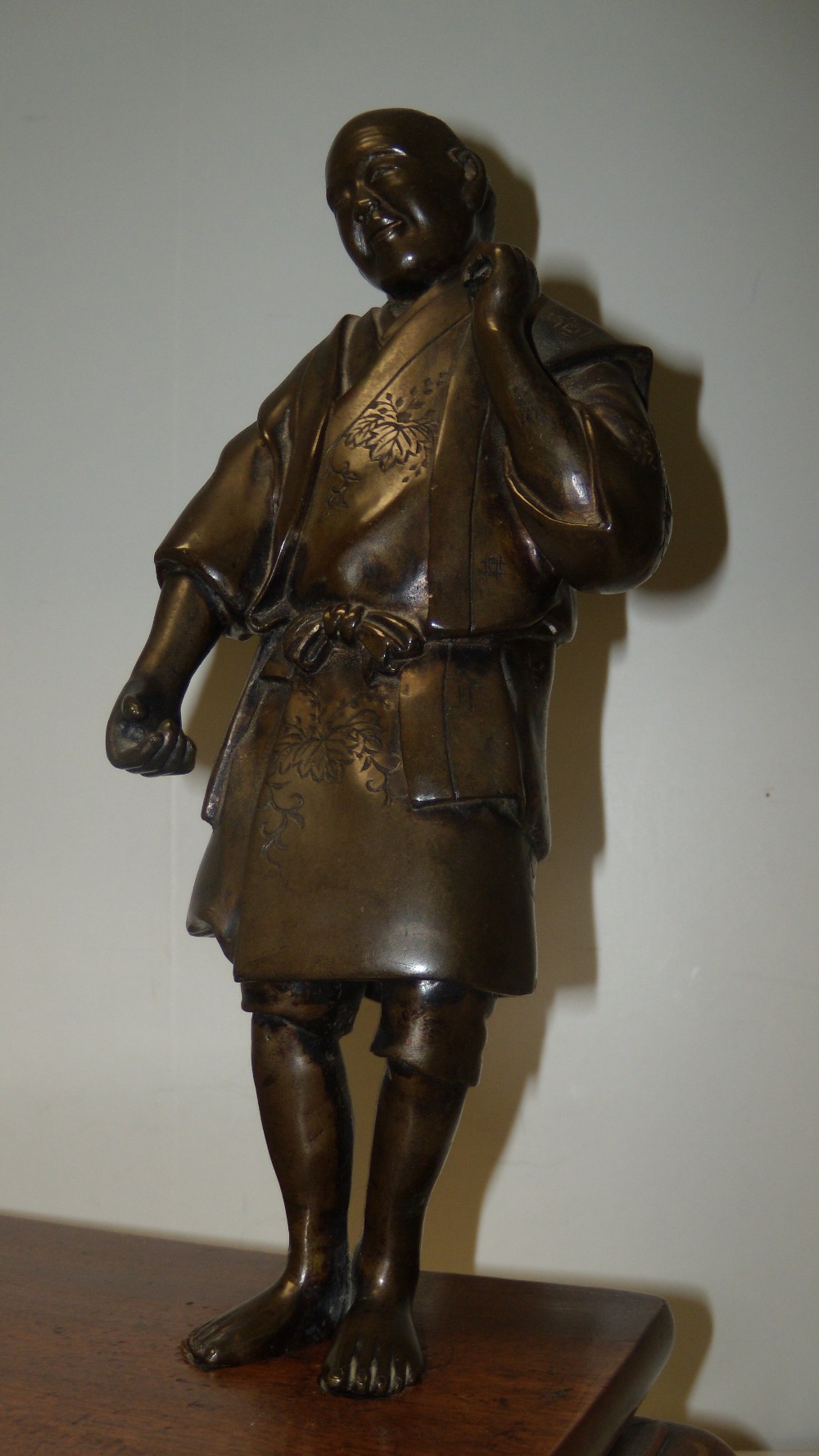 A late 19th/early 20th century bronze figure of a man standing to one corner of a wooden stand - Image 2 of 3