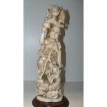 An early 20th century marine ivory group of a luohan standing on wave lashed rocks with a dragon