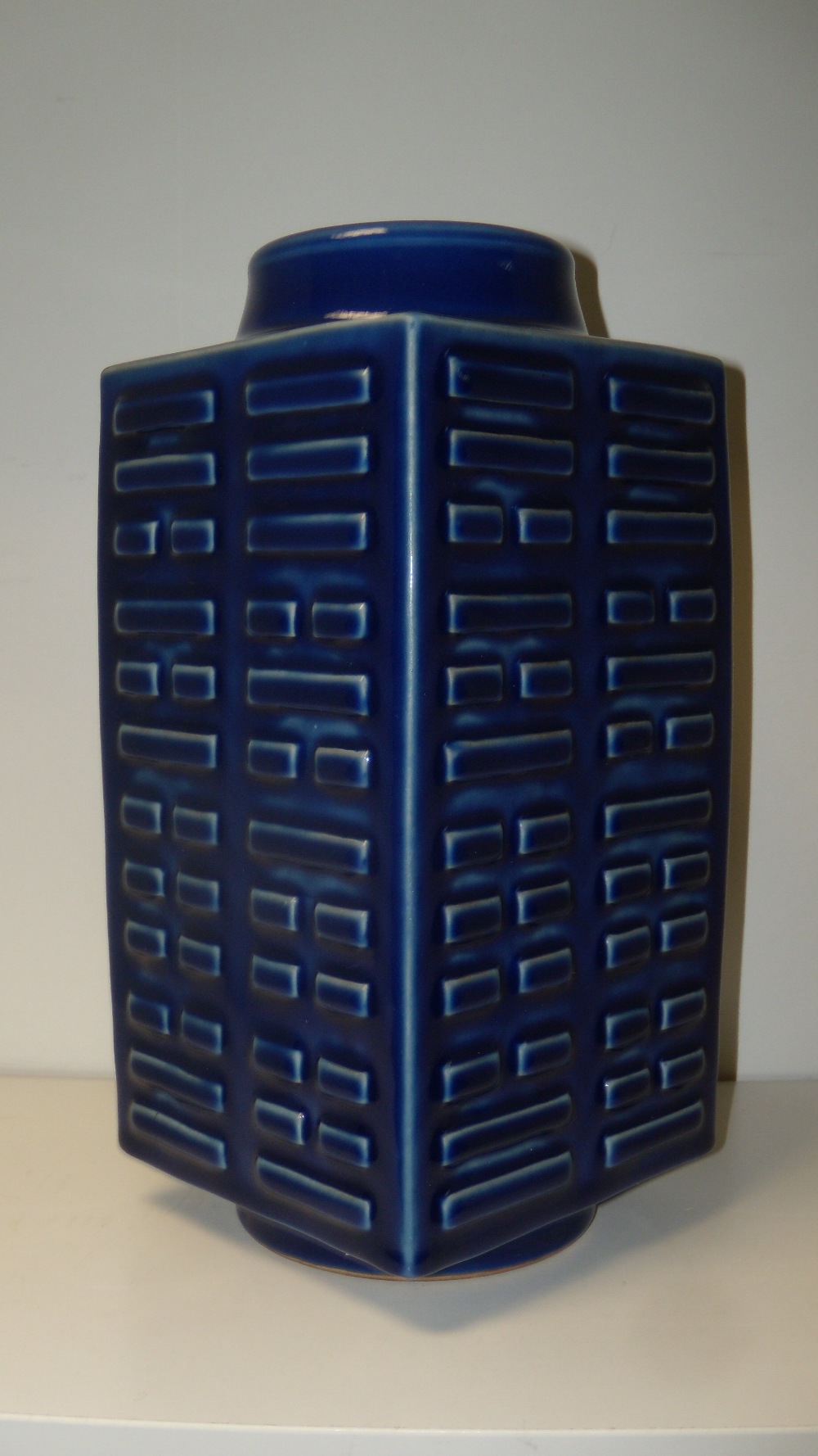 A blue cong shaped vase, the panel sides of the square sectioned shape moulded in relief with