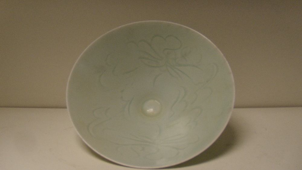 A yingqing bowl, the interior of the conical shape incised with three flower heads beneath the misty