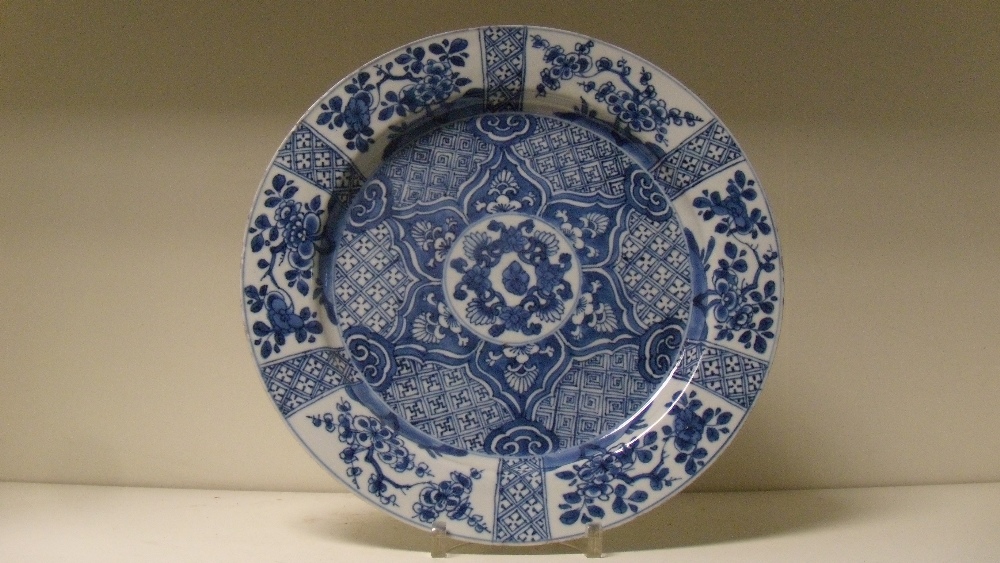 An 18th century blue and white dish painted with brocade and flower panels radiating around a