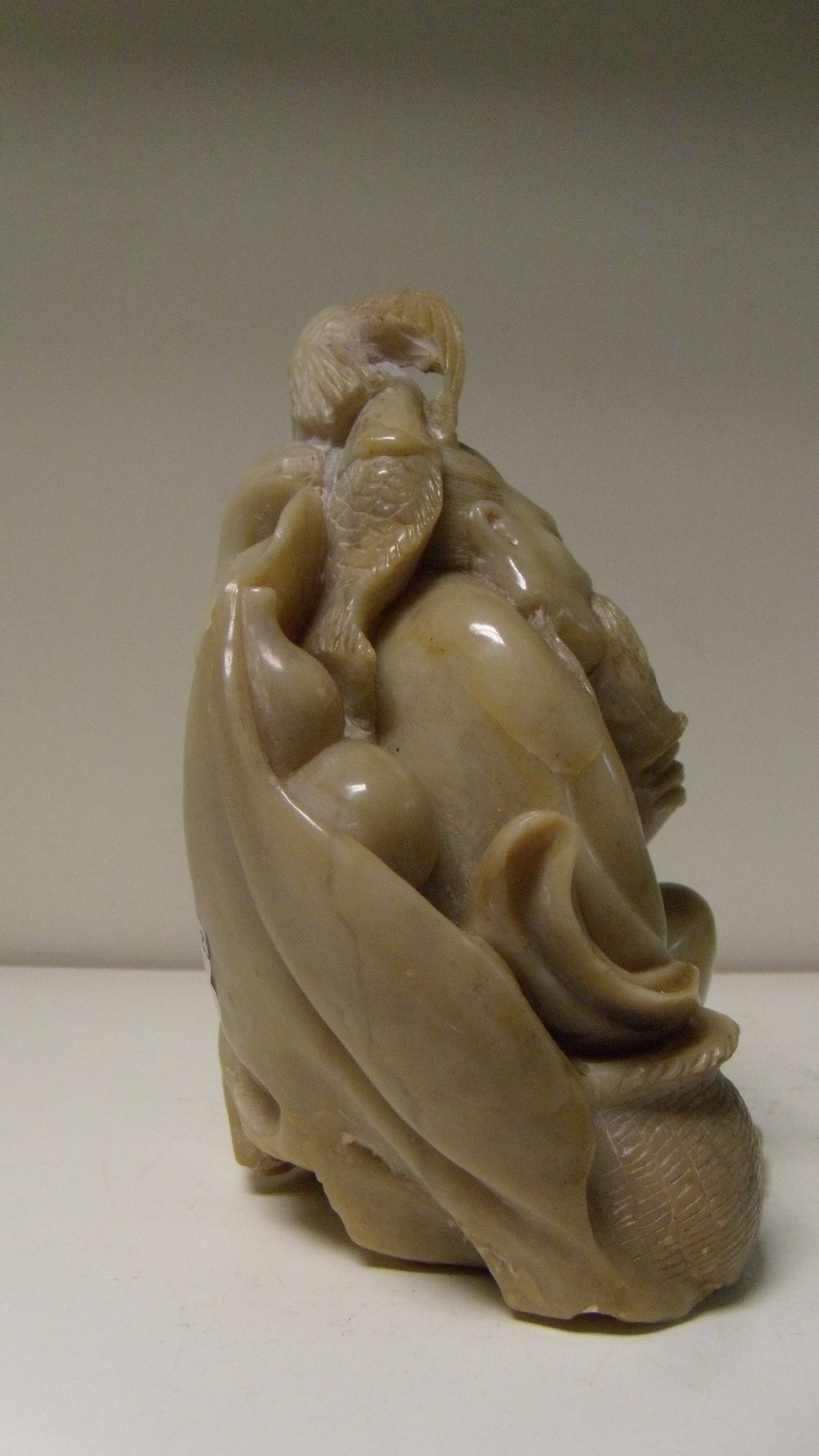 A buff grey soapstone figure of a fisherman, seated in a slumber, his left hand on his beard and his - Image 3 of 4