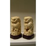 A pair of early 20th century ivory dogs of Fo with wood stands, the seated beasts wearing mask