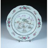 A late 18th century famille rose plate painted with four French warships moored off a coastal depot,