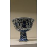 A Ming style blue and white stem cup, the exterior of the bowl painted with lotus scrolling around