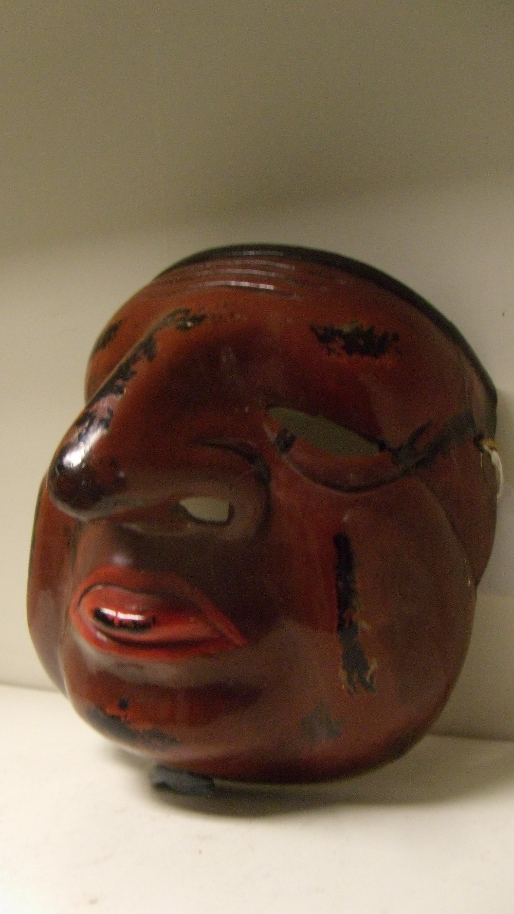 A lacquer mask, possibly of Shin Sotoku, a red tongue protuding from the brown face with black hair,