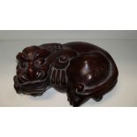 A hardwood qilin, the fierce eyed mythical beast reclining with a lingzhih fungus in its teeth, 23cm