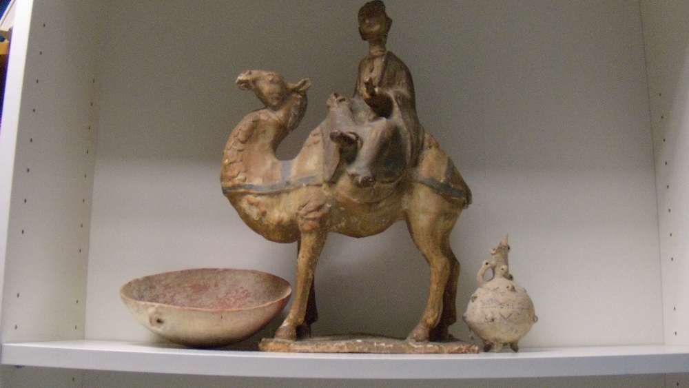 A Tang style camel, the figure riding side saddle on its back holds a scroll in his left hand, muted