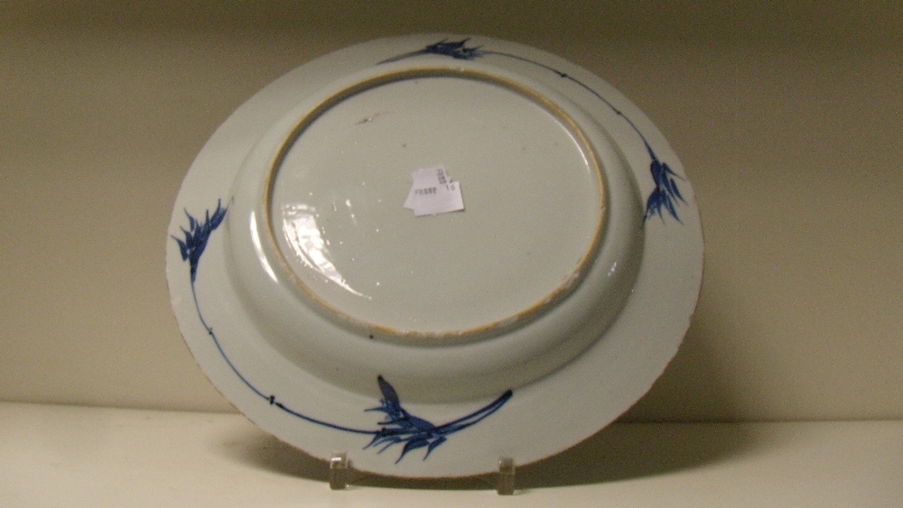 An 18th century blue and white dish painted with brocade and flower panels radiating around a - Image 2 of 2
