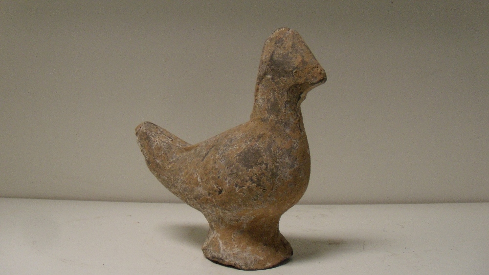 A Han dynasty grey pottery figure of a chicken, the bird supported on a flared circular foot, traces