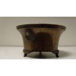 A 19th century bronze censer, the concave sides tapering to the three feet and applied with mask