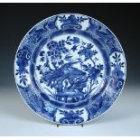 A blue and white dish, period of Kangxi, centrally painted with birds about a rock amongst peonies