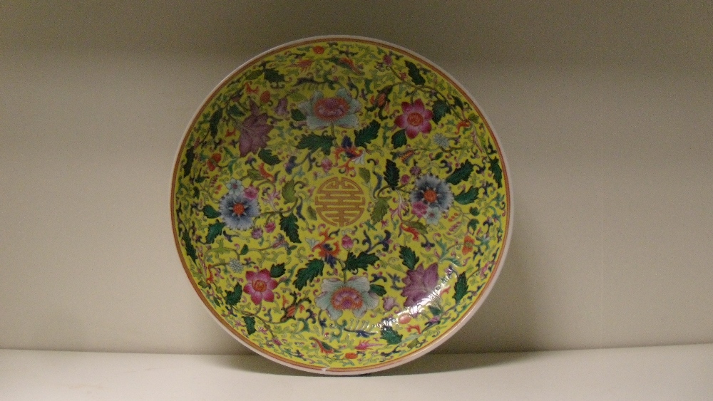 A yellow ground dish, painted with flowers scrolling around the central gilt shou character within