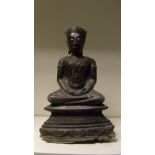 A Northern Thai or Burmese bronze Buddha, serenely seated cross legged on a throne of rounded