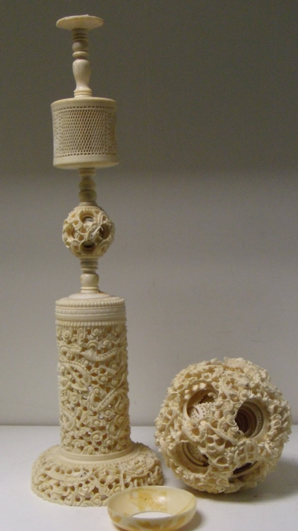 A late 19th/early 20th century ivory ball within ball carving and stand, the exterior of the ball