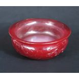 A Peking red glass butter tea bowl, the rounded sides below the flared rim carved with two dragons