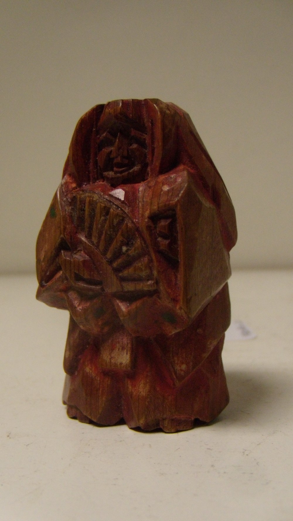 A Nara ningyo ittabori netsuke depicting a Noh actor standing holding a fan, the soft wood painted