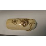 A late 19th/early 20th century ivory wrist rest, the round arched form carved in relief at one end